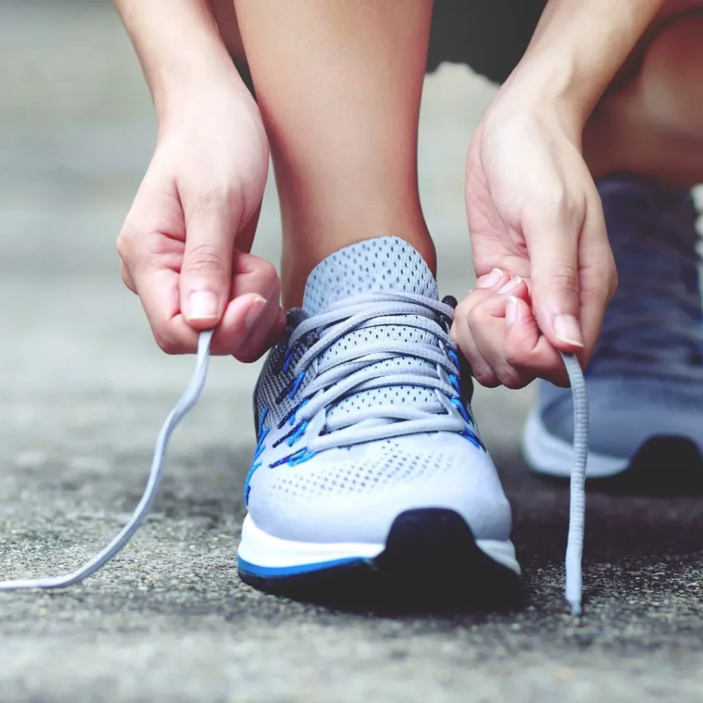 A person tying her shoelace in the context of fitness and wellness, emphasizing the beginning of a healthy and active lifestyle.