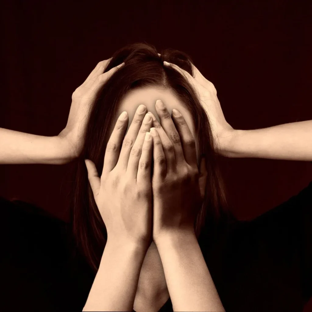 An individual with hands on her head, covering her face in an expression of mental distress, embodying the complexities of 'Mental Health' topics